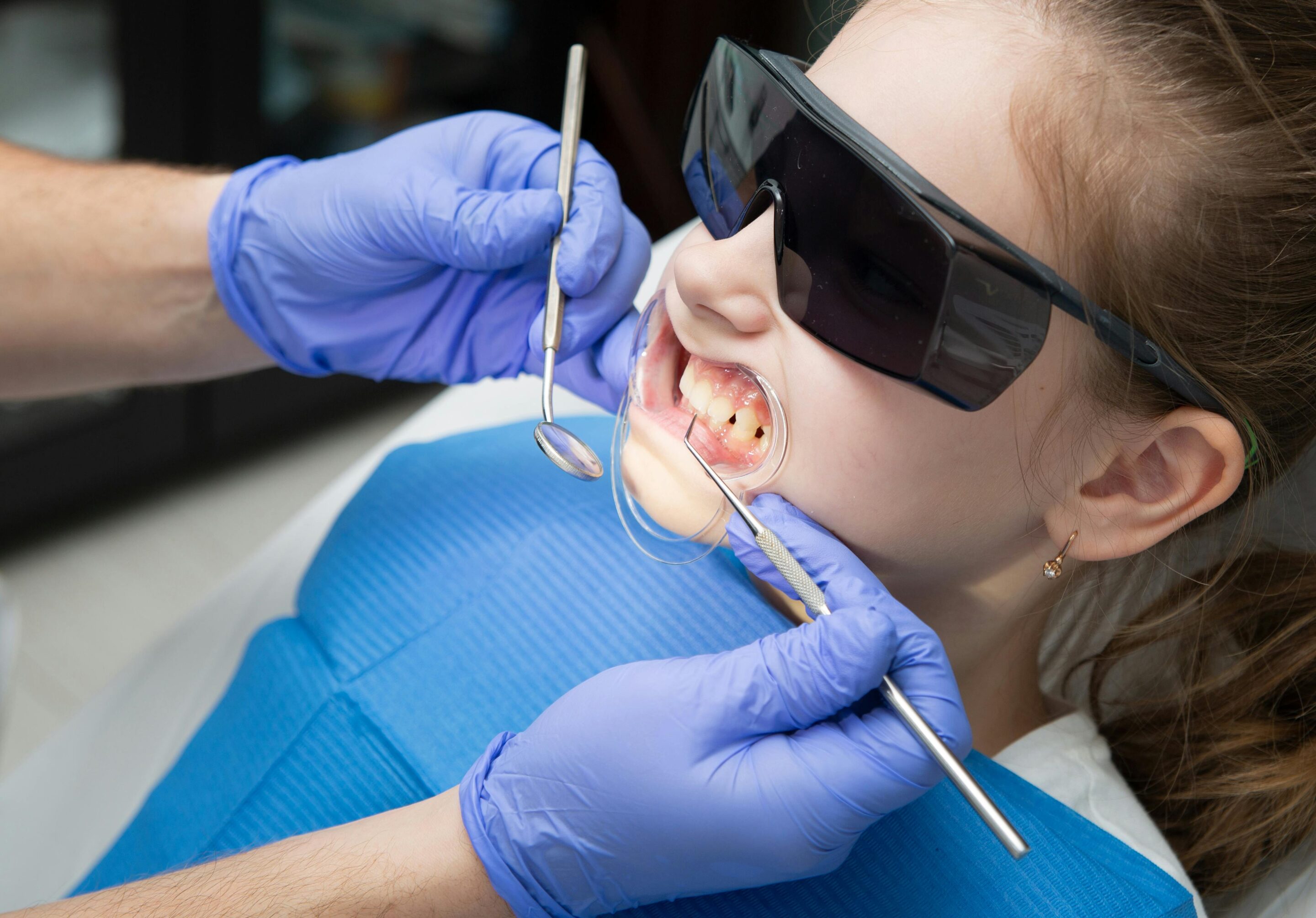 Child receiving pediatric dental care with protective glasses